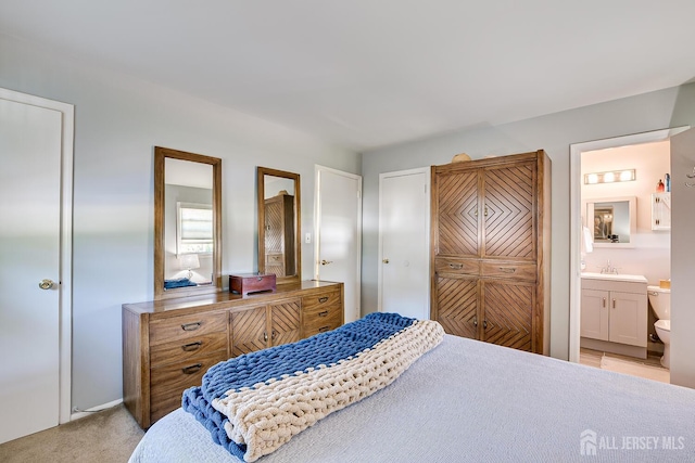 carpeted bedroom with ensuite bath and sink