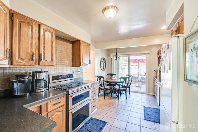 kitchen with decorative backsplash, white refrigerator, range with two ovens, a notable chandelier, and light tile patterned flooring