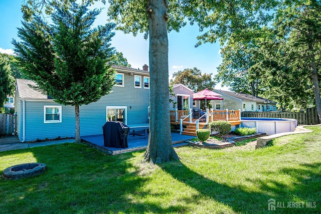 back of property featuring a yard, a fire pit, and a pool side deck