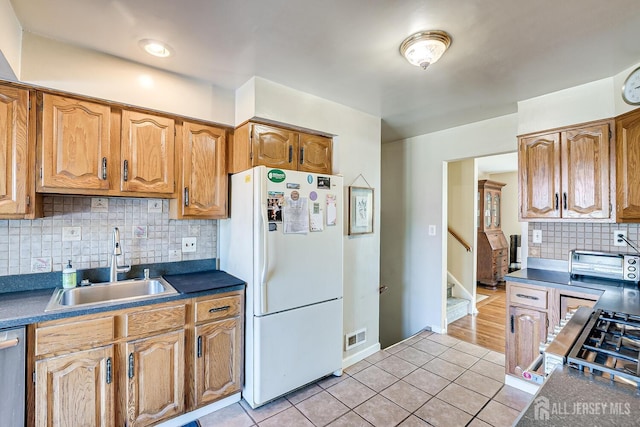 kitchen featuring backsplash, white refrigerator, light tile patterned flooring, and sink