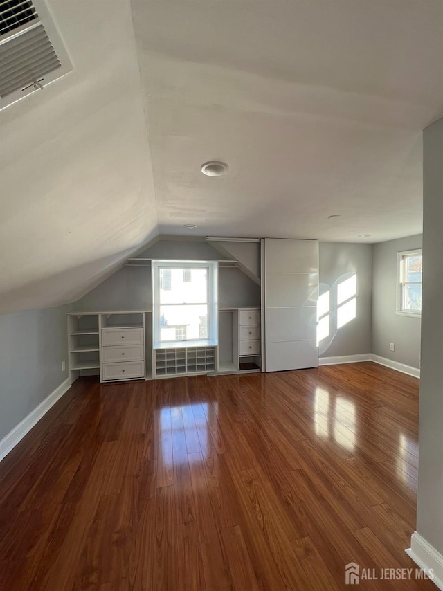 bonus room featuring wood finished floors, lofted ceiling, healthy amount of natural light, and baseboards