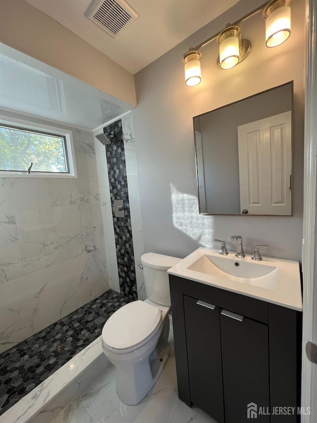 full bath with marble look tile flooring, vanity, a stall shower, and toilet