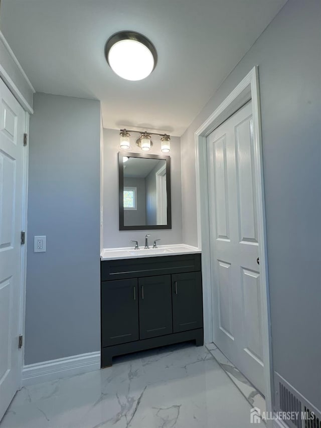 bathroom with marble look tiles, vanity, and baseboards