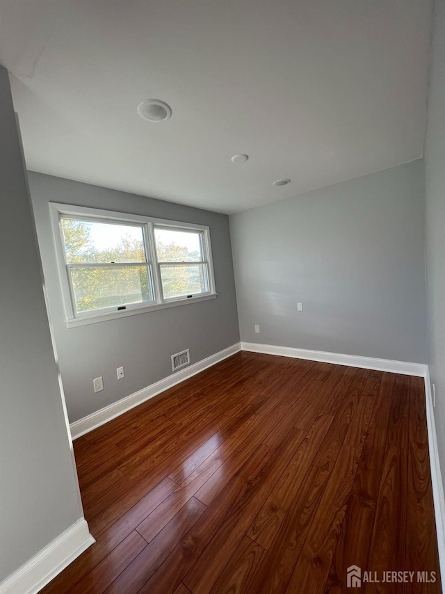 spare room featuring dark wood-style floors and baseboards