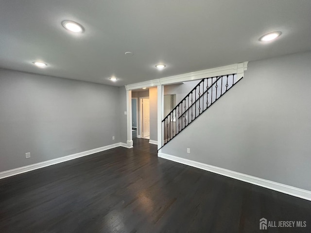 basement with baseboards, dark wood finished floors, recessed lighting, and stairway