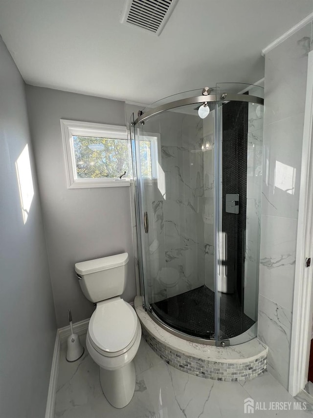 full bathroom with marble finish flooring, toilet, a marble finish shower, and baseboards