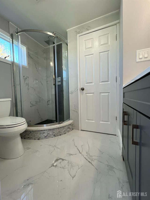 bathroom with toilet, marble finish floors, a marble finish shower, and vanity
