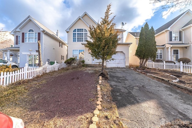 view of front of house with driveway, a garage, and fence