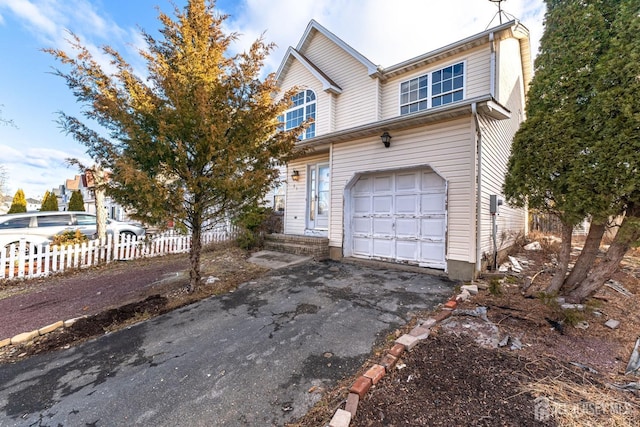 view of front of property with aphalt driveway, fence, and a garage