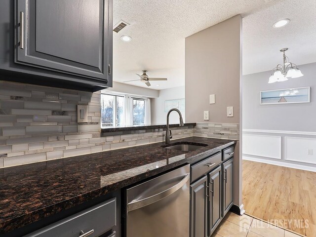 kitchen with dark stone countertops, sink, stainless steel dishwasher, and a textured ceiling