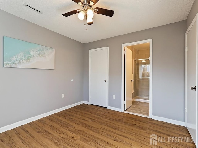 unfurnished bedroom with ceiling fan, ensuite bath, and light hardwood / wood-style flooring