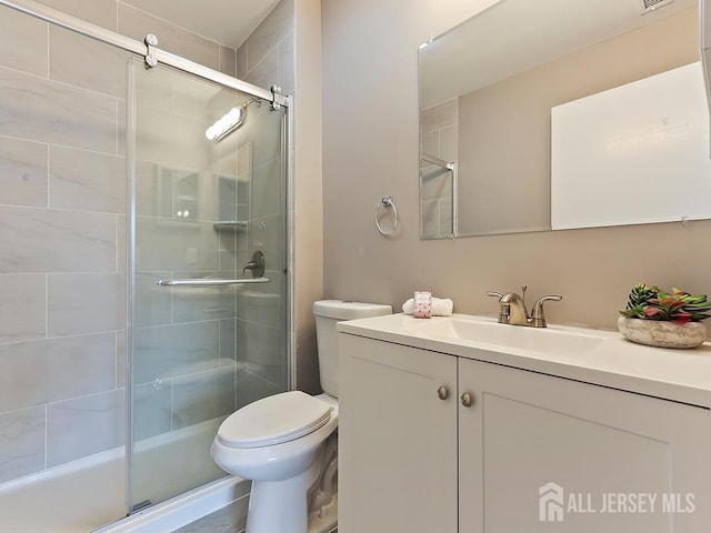 bathroom with vanity, a shower with door, and toilet