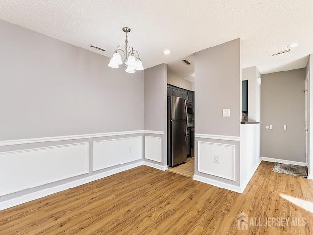 kitchen with stainless steel refrigerator, light hardwood / wood-style floors, and a textured ceiling