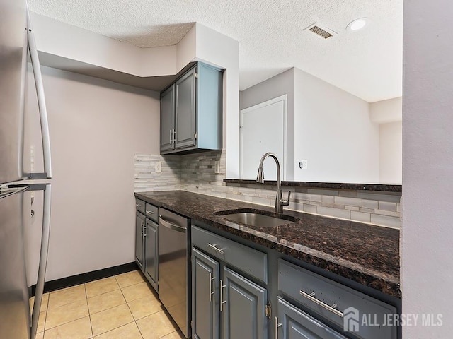 kitchen with sink, light tile patterned floors, dark stone countertops, gray cabinetry, and stainless steel appliances