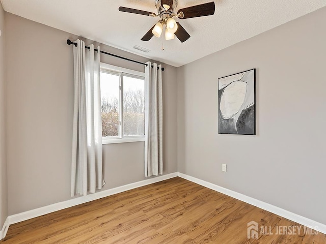 empty room featuring ceiling fan, light hardwood / wood-style flooring, and a textured ceiling