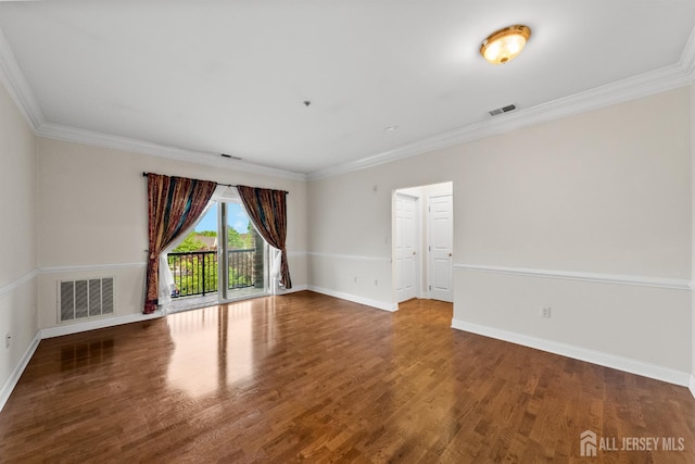 spare room featuring wood finished floors, crown molding, and baseboards
