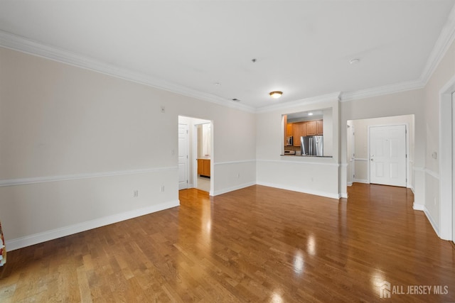 unfurnished living room featuring wood finished floors, ornamental molding, and baseboards