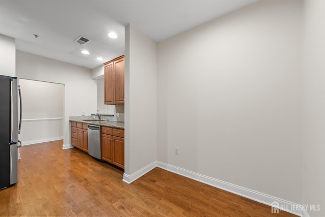 kitchen featuring stainless steel appliances, baseboards, light wood-style flooring, recessed lighting, and a sink