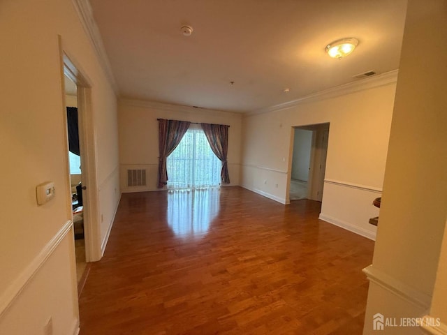 unfurnished room featuring crown molding, wood finished floors, a smoke detector, and baseboards