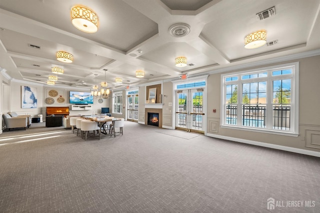 dining space with coffered ceiling, carpet floors, a chandelier, a glass covered fireplace, and french doors