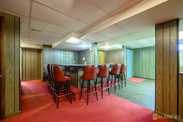 bar with a paneled ceiling and wood walls