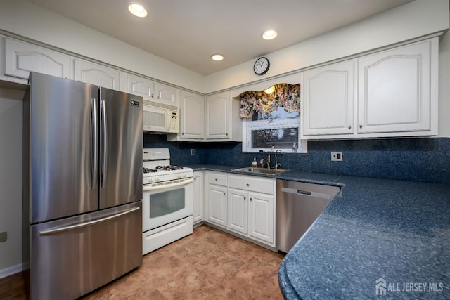 kitchen with backsplash, appliances with stainless steel finishes, sink, and white cabinetry