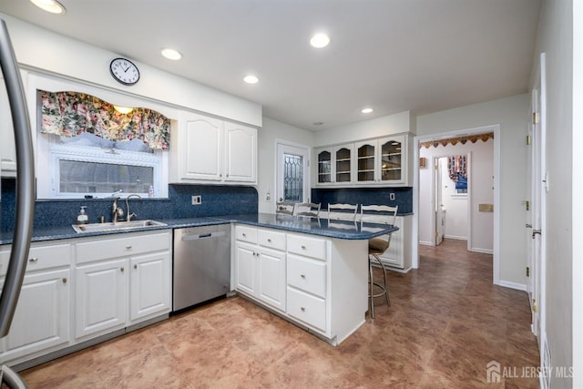 kitchen with white cabinetry, kitchen peninsula, a breakfast bar area, stainless steel appliances, and sink