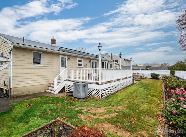 rear view of property featuring a wooden deck, a yard, and central air condition unit