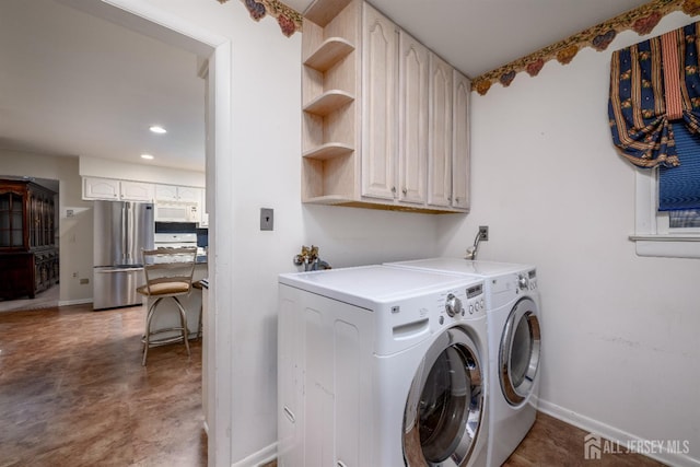 laundry room featuring washer and clothes dryer and cabinets