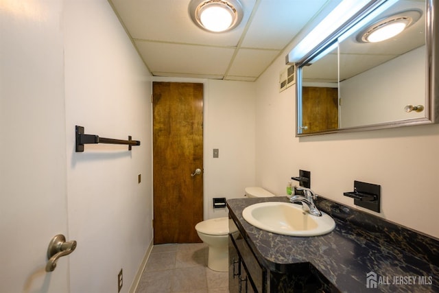 bathroom with a drop ceiling, toilet, and vanity