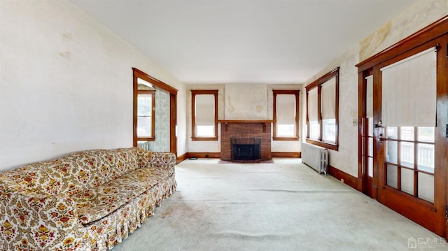 living room with carpet flooring, radiator, and a brick fireplace