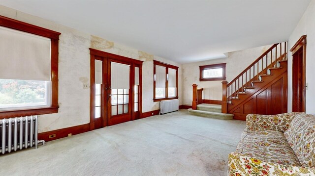 unfurnished living room featuring radiator heating unit and light colored carpet