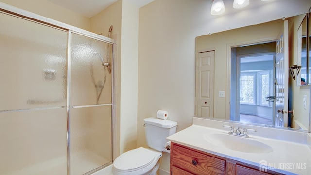 bathroom featuring a shower with door, vanity, and toilet