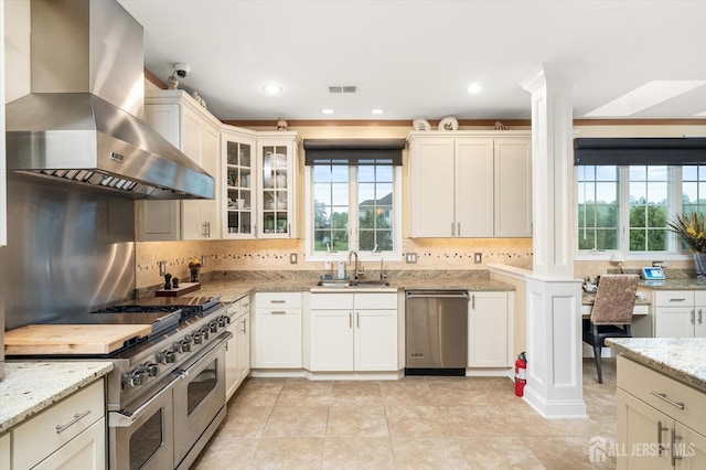 9 Bouvier Ln, South Brunswick, NJ 08816 - kitchen with wall chimney range hood, appliances with stainless steel finishes, a sink, ornate columns, and tasteful backsplash
