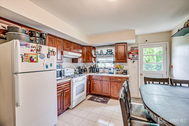 84 Kossuth St, Piscataway, NJ 08854 - kitchen with white appliances, under cabinet range hood, light countertops, light tile patterned floors, and brown cabinets