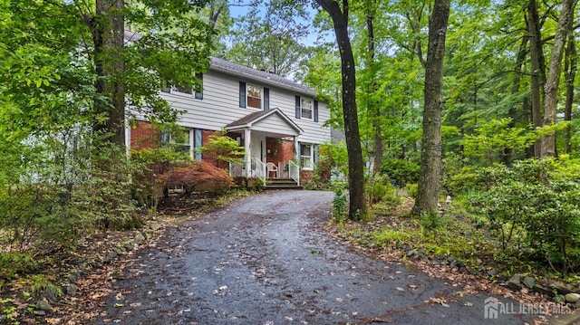 910 Curtis Pl, North Brunswick, NJ 08902 - view of front of property featuring driveway, brick siding, and a porch