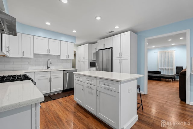 910 Curtis Pl, North Brunswick, NJ 08902 - kitchen with stainless steel appliances, extractor fan, decorative backsplash, a center island, and white cabinets