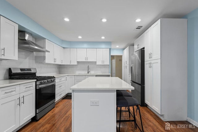 910 Curtis Pl, North Brunswick, NJ 08902 - kitchen with stainless steel appliances, wall chimney range hood, a kitchen bar, a center island, and white cabinetry