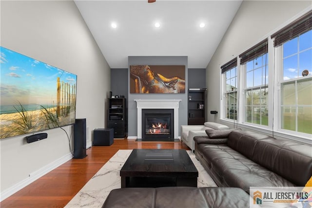 living room featuring recessed lighting, high vaulted ceiling, a fireplace with flush hearth, and wood finished floors