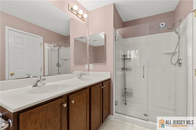 full bath featuring double vanity, a sink, a stall shower, and tile patterned floors