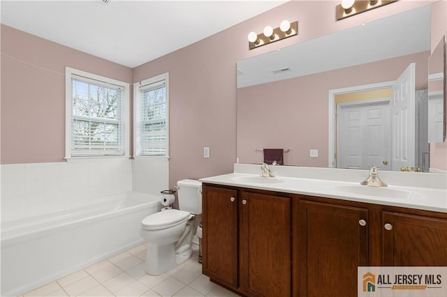 bathroom featuring double vanity, a bathtub, tile patterned flooring, a sink, and toilet