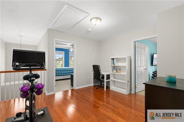 home office with baseboards, ceiling fan, attic access, and wood finished floors