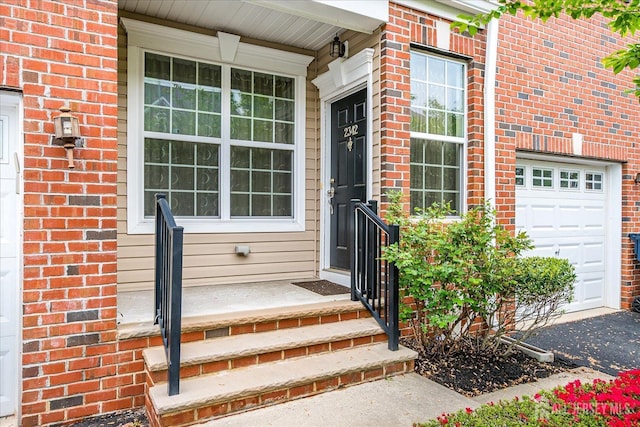 doorway to property with a garage, brick siding, and asphalt driveway