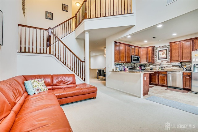 living area featuring recessed lighting, a high ceiling, light colored carpet, and stairs