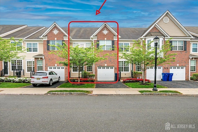 view of property featuring driveway, a garage, and brick siding