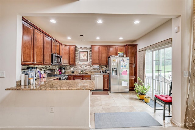 kitchen featuring appliances with stainless steel finishes, decorative backsplash, light stone counters, brown cabinetry, and recessed lighting