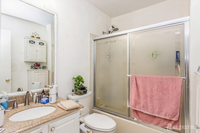 full bath featuring combined bath / shower with glass door, vanity, and toilet