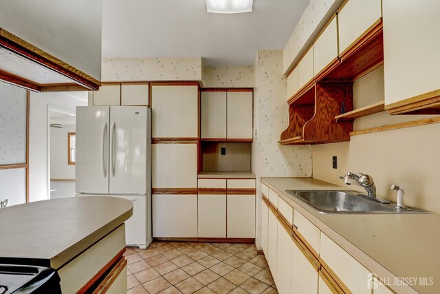 kitchen with white refrigerator, sink, and light tile patterned floors