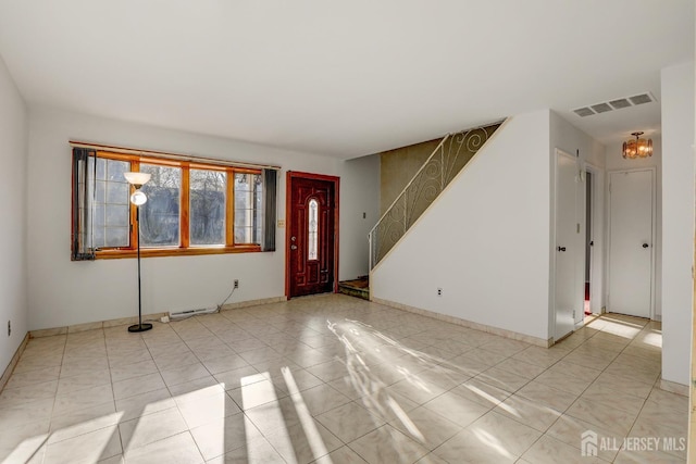 tiled entryway with a chandelier