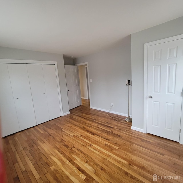 unfurnished bedroom featuring baseboards, light wood-style flooring, and a closet